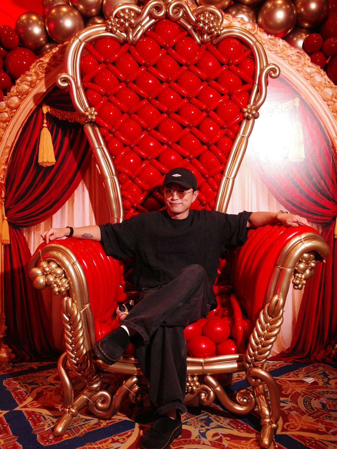 Ting Yu Wong sentado en un trono de globos rojo y dorado